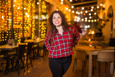 Portrait of smiling young woman standing on chair