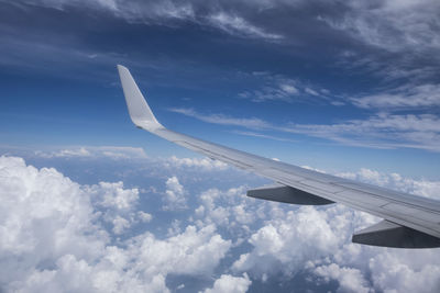 Airplane wing over clouds against blue sky