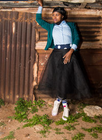 Full length of woman looking away standing against wall