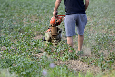 Low section of man with motocultivator on field
