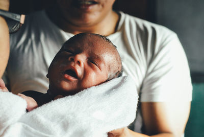 Close-up of hands holding newborn baby in hospital