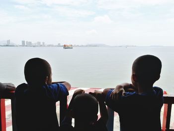 Rear view of people looking at sea against sky