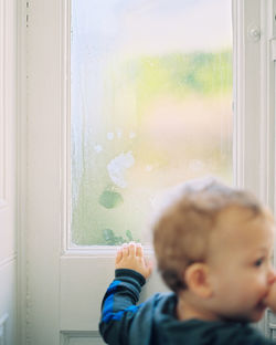 Portrait of boy looking through window