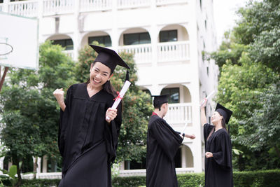 Cheerful student with clenched fist wearing graduation gown