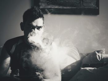 Portrait of young man smoking at home