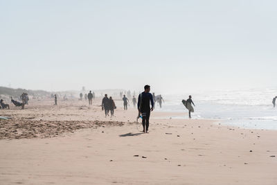 People walking on beach against clear sky