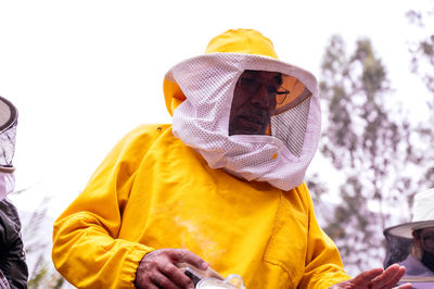 A beekeeper in a protective suit works with bees. 