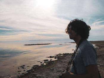 Man looking at sea shore against sky during sunset