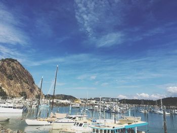 Sailboats moored at harbor against blue sky