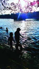 Silhouette men in water at sunset