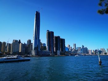 Sailboats in city by buildings against clear sky