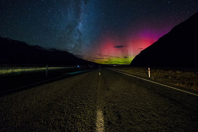 Road amidst illuminated mountains against sky at night