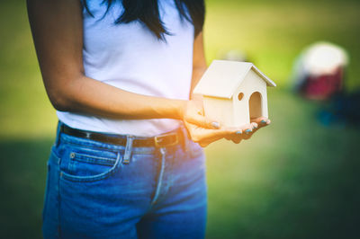 Midsection of woman holding model house