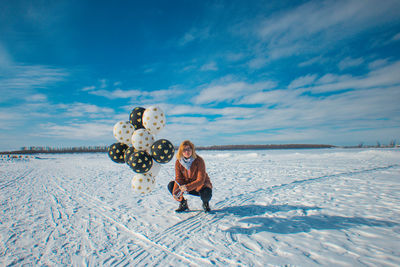 Portrait of woman holding balloons on snow covered land