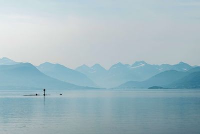 Scenic view of lake and mountains against morning fog 