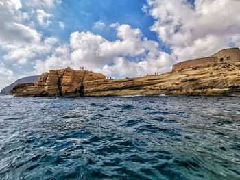 Rock formations by sea against sky