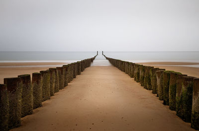 Wooden posts against sky at beach