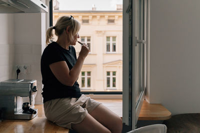 Side view of woman vaping at home