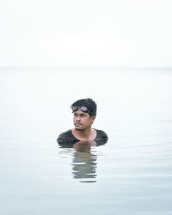 Portrait of young man swimming in sea against clear sky