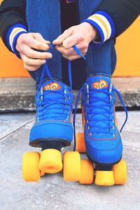 Girl lacing up blue roller skates and getting ready for skate session