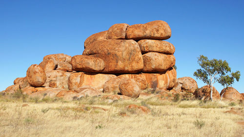 Rock formations on landscape against clear blue sky