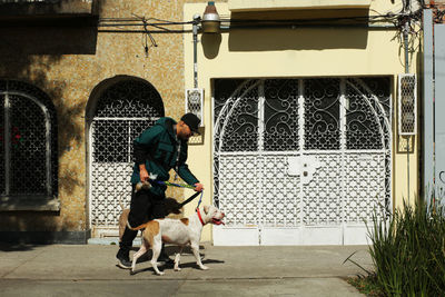 Man and dog on street against building