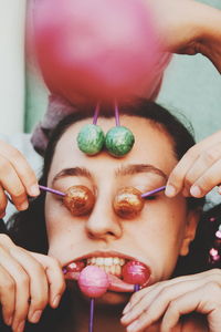 Cropped hands covering woman face with lollipops