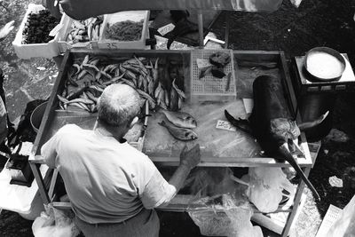 High angle view of man selling fishes at market stall