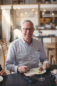 Portrait of smiling senior man having lunch at table in restaurant