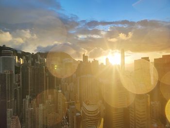 Panoramic view of hong kong against sky during sunset through window with raindrops