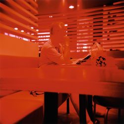 Side view of man sitting at illuminated table