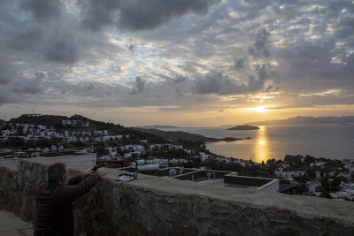 Scenic view of sea and buildings against sky during sunset