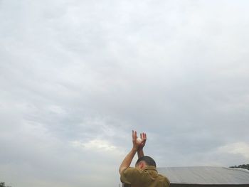 Low angle view of person hand against sky