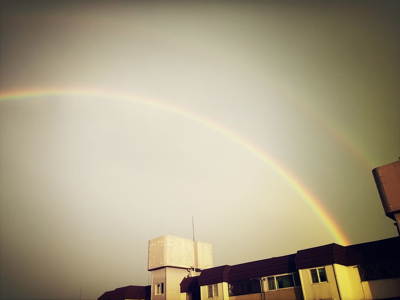 architecture, built structure, building exterior, rainbow, low angle view, sky, copy space, building, high section, outdoors, no people, city, multi colored, vapor trail, nature, clear sky, scenics, sun, sunset, beauty in nature