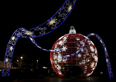 Close-up of illuminated ferris wheel against sky at night