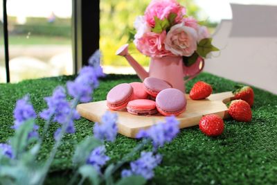 Close-up of macaroons and strawberries by flowers on table