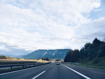 Road by mountains against sky