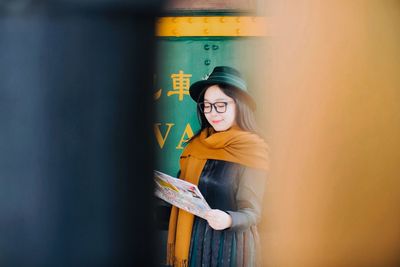 Young woman reading newspaper at railroad station