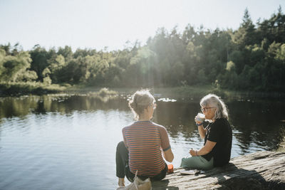 Two senior women sitting on rock at lakeshore