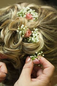 Cropped hand of hairdresser adjusting flowers in hair