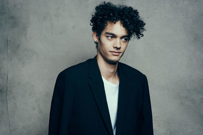 Portrait of young man standing against wall