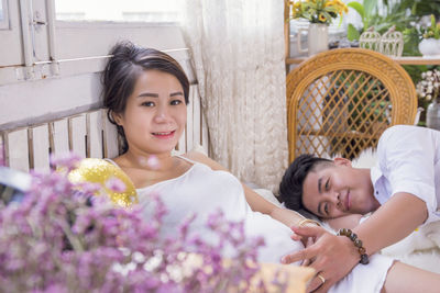 Portrait of pregnant woman smiling with boyfriend lying on bed