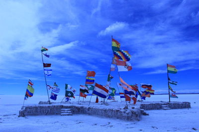 Low angle view of flags on snow covered land against sky