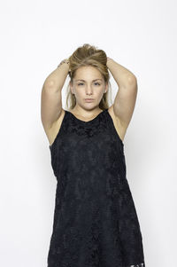 Portrait of young woman standing against white background