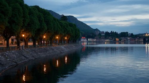 Scenic view of lake by buildings against sky at dusk