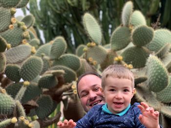 Portrait of happy father with cute son against cactus plants