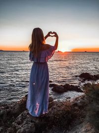 Rear view of woman at beach during sunset