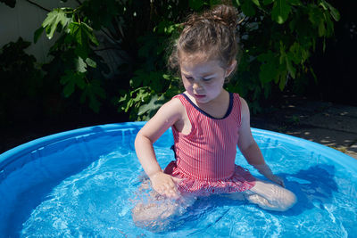 Cute toddler playing in the water basin in the backyard