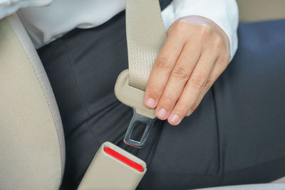 Midsection of woman wearing seat belt in car