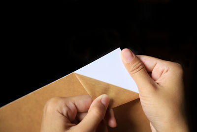 Midsection of person holding paper against black background